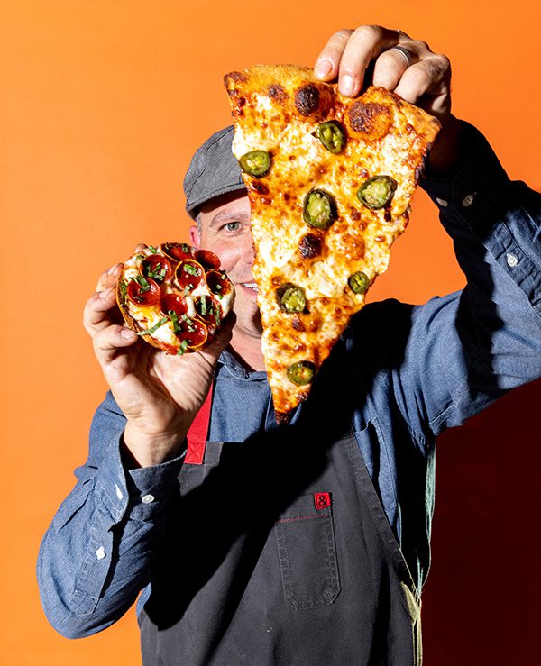 Chef holding a pizza slice and a pizza bagel from new LA restaurant Bagel + Slice.