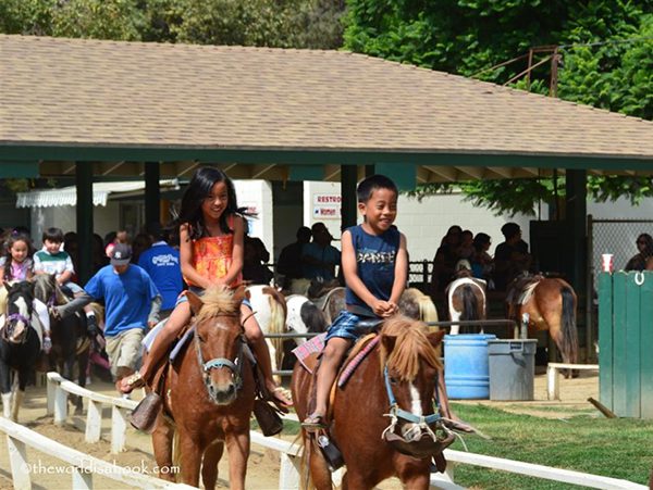 Smiling children riding ponies at Griffith Park Pony Rides. 